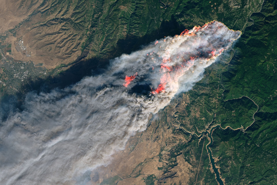 Satellitenbild von einem großen Waldbrand in Kalifornien mit dichten Rauchwolken.