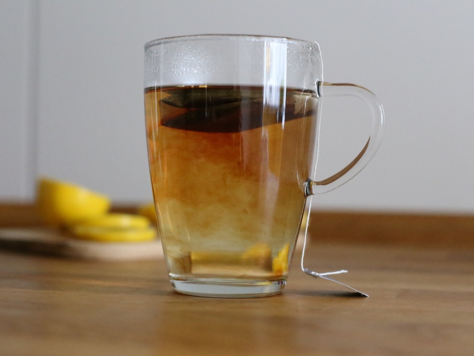 Die Farbe des Tees breitet sich langsam in der durchsichtigen Tasse aus.