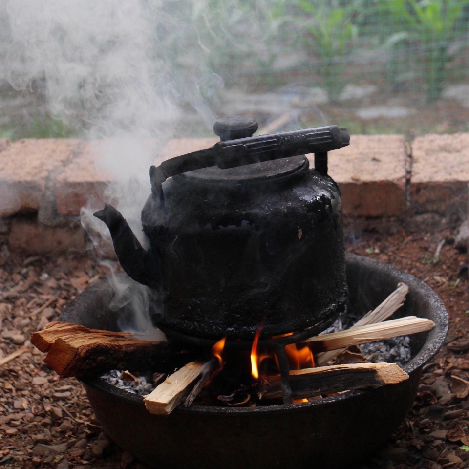 Teekanne steht auf offenem Feuer und Wasser siedet.
