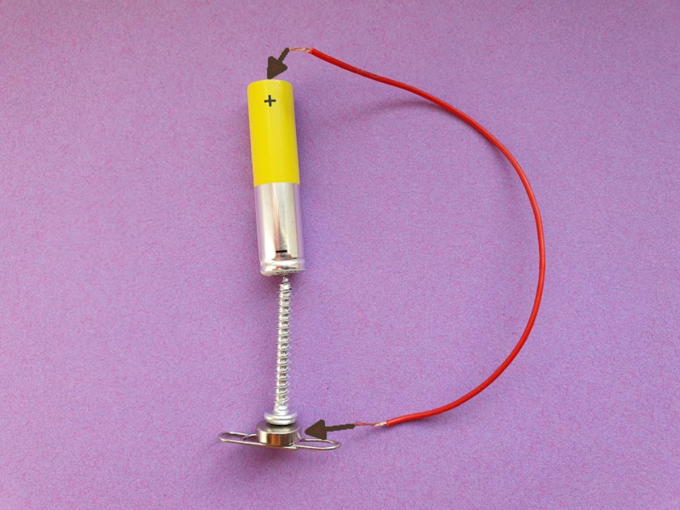 einfacher Unipolarmotor aus einer Batterie, einer Schraube, einem Magnet, einer Büroklammer und einem Draht
